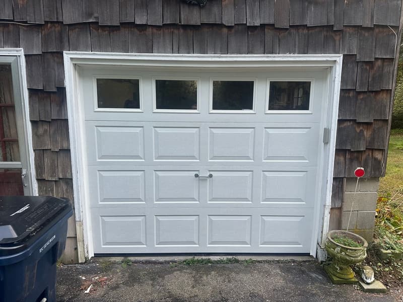 White raised-panel garage door with windows illuminated at night